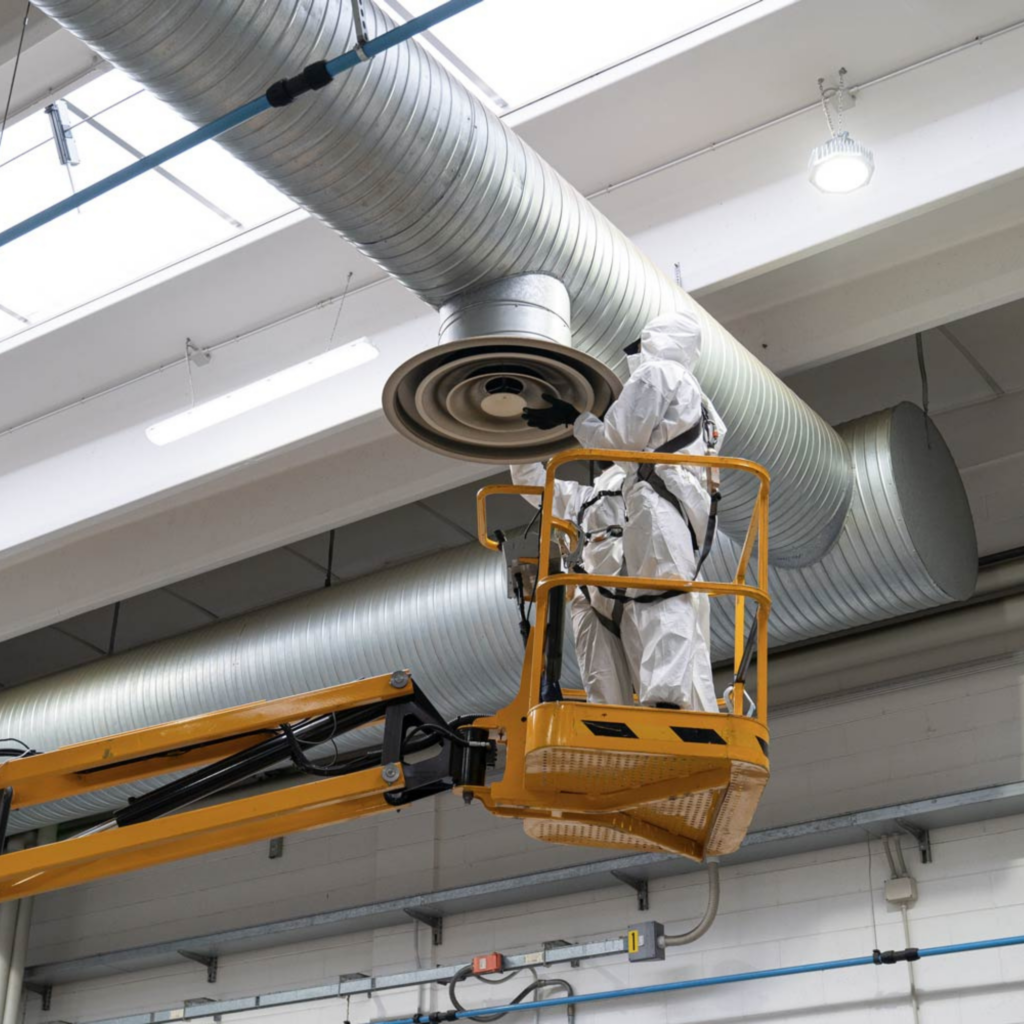 Tecnico su piattaforma elevatrice installa componenti di un impianto aeraulico in un edificio industriale, servizio offerto da GSG Air Conditioned srl